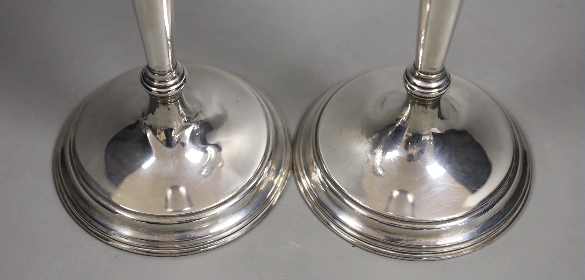 A pair of North American sterling candlesticks, with tapering stems, on circular bases, height 35.7cm, weighted.